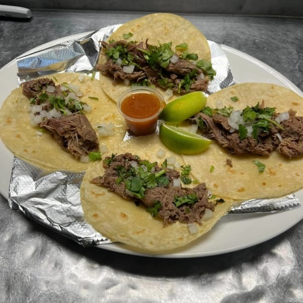 Four Primos De Tico's Mexican street tacos with shredded beef, onion, cilantro, lime, and salsa.