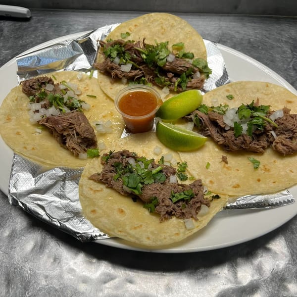 Four Primos De Tico's Mexican street tacos with shredded beef, onion, cilantro, lime, and salsa.